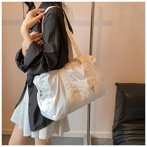 Detailed view of white nylon shoulder bag with pleated texture and functional pockets