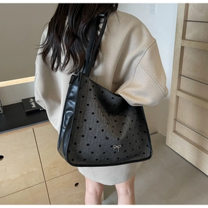 Detailed back view of a large grey fabric tote bag with black polka dots and metal bow charm