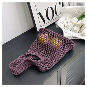 Detail view of purple woven mesh handbag holding two lemons to show storage capacity