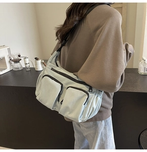 Detail of light blue nylon crossbody bag with dual front pockets and adjustable strap