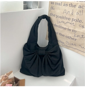 Détail du sac cabas en denim noir avec un grand nœud décoratif et une poignée à nœud chic