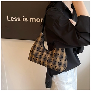 Dettaglio della borsa hobo con motivo scozzese marrone, cuori neri e fibbia a fiocco in metallo
