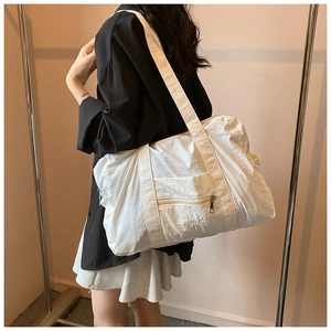 White nylon tote bag with front zipper pocket and VEILA logo on model shoulder