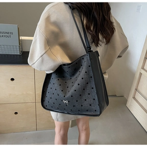 Detail view of large tote bag with grey polka dot wool fabric and black leather straps