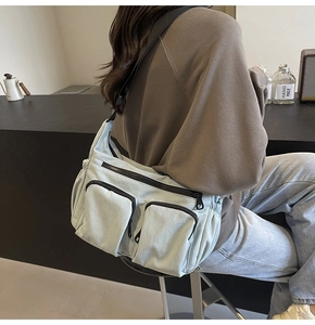 Detail of light grey multi-pocket nylon crossbody bag with adjustable wide strap