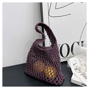Detail of handwoven purple mesh tote bag with lemon interior decoration on black table