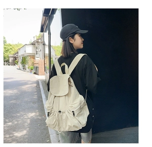 Outdoor view of a beige nylon backpack with drawstring closure and large capacity