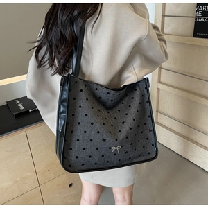 Detail of grey fabric tote bag with black polka dots and embroidery on model shoulder