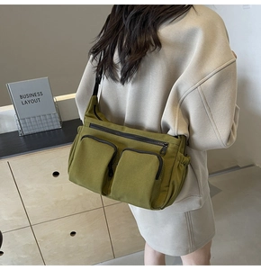Detailed view of olive green canvas crossbody bag showing side drawstring and zip pockets