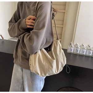 Detail of beige pleated nylon crossbody bag showing dumpling shape and drawstring texture