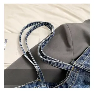Detail view of denim tote bag showing double handles and distinct yellow contrast stitching