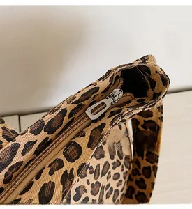 Close-up detail of smooth metal zipper and leopard print canvas texture on the crossbody bag