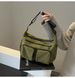 Close-up of olive green canvas crossbody bag with multiple pockets and zipper details