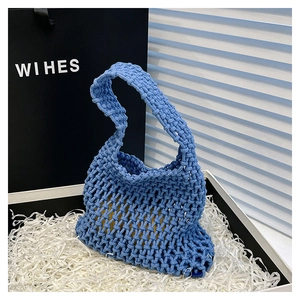 Detail of blue woven handbag showing intricate crochet texture with yellow inner pouch insert