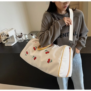 Side view of white canvas crossbody bag with cherry embroidery and yellow straps