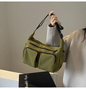 Detail of olive green canvas crossbody bag with dual zipper pockets and black strap