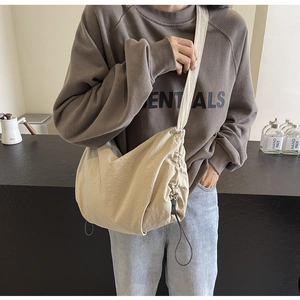 Detail of khaki drawstring crossbody bag with adjustable strap on a model outfit