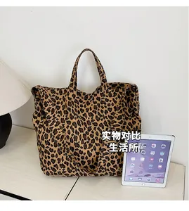 Detail view of large canvas leopard print tote bag next to an iPad for size comparison