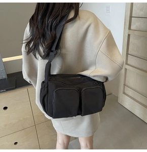 Close-up of black crossbody bag with multi-pocket design and adjustable strap on a model