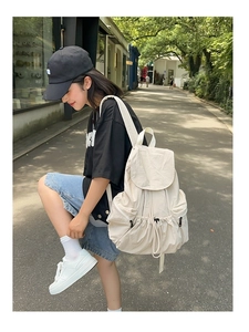 Detail of a cream nylon backpack with drawstring closure and large capacity design