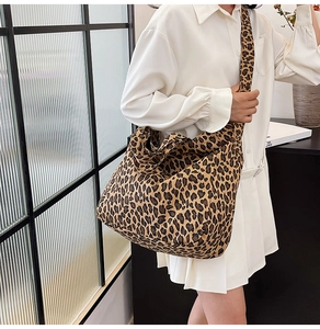 Detail of the wide shoulder strap and leopard print canvas texture on the crossbody bag