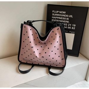 Minimalist pink and black polka dot tote bag with bow details on a marble surface