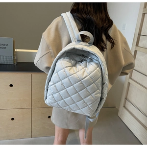 Detail eines hellgrauen gesteppten Rucksacks mit Rautenmuster und Polsterträgern