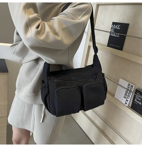 Close-up of black nylon crossbody bag featuring double front zipper pockets and side pouch