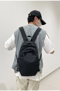Rear view of model wearing a black washed fabric backpack with minimalist design details