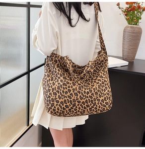 Detail shot of a large leopard print canvas tote bag worn as a shoulder bag on a model