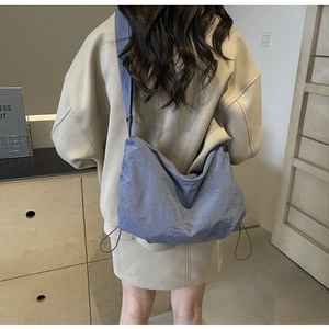 Detail of navy nylon crescent crossbody bag with drawstring accents and wide strap