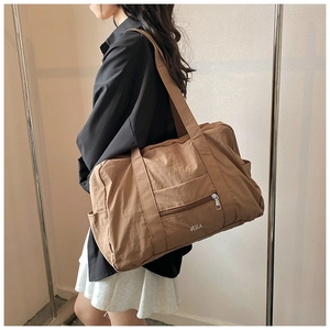 Detailed view of brown nylon tote bag with side pockets and white VEILA logo print