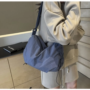 Blue nylon crescent crossbody bag with pleated texture and adjustable strap on model