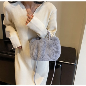Close-up of soft grey plush crossbody bag with woven handle on white knit dress