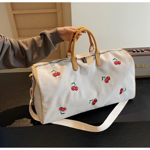Close-up of cherry embroidery and leather handle on a large canvas tote bag