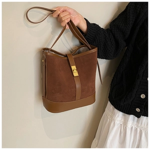 Close-up of brown suede bucket bag with gold twist lock and leather stitching detail