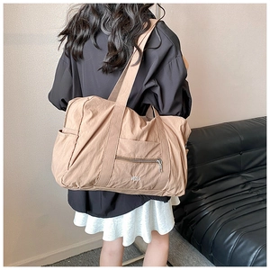 Detail view of khaki nylon shoulder bag with zipper pocket and athletic embroidery