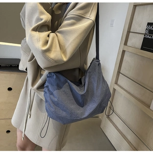 Blue nylon crossbody bag with drawstring detail and adjustable strap for daily use