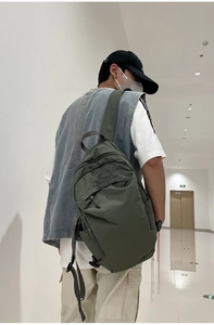 Detail view of the dark green washed fabric backpack showing side zip pocket and straps