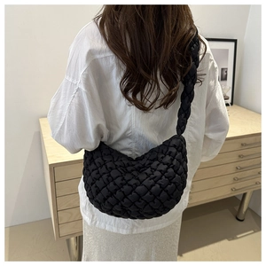 Vista trasera de una modelo con un bolso bandolera negro acolchado de media luna