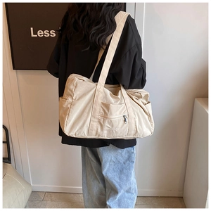 Detail view of beige nylon shoulder bag showing side pocket and durable fabric texture