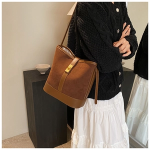 Detail of vintage brown faux suede bucket bag with elegant golden metal lock closure