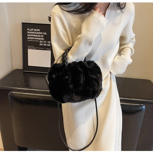 Detail of plush black faux fur shoulder bag with woven handle and slim strap