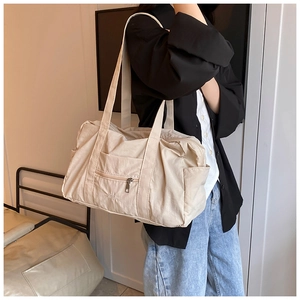 Close-up of beige nylon shoulder bag with functional pockets and zipper detail