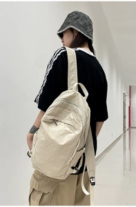 Detail of beige washed fabric backpack featuring side buckles and Flyto logo on back