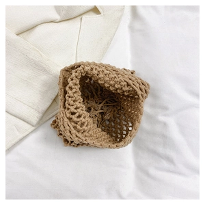Detailed view of handmade woven straw tote bag with inner drawstring pouch on fabric
