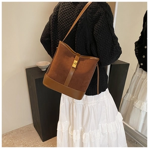 Detail of vintage brown suede bucket bag with gold lock and leather shoulder strap