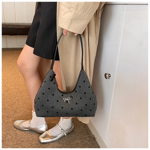 Borsa hobo in denim grigio a pois neri e fiocco bianco indossata con un trench beige chic