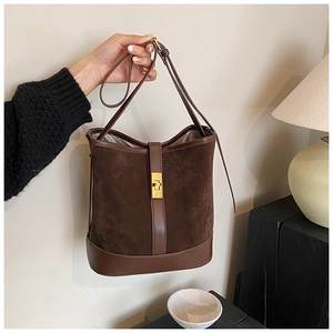 Detail of dark brown suede bucket bag with gold metal twist lock and leather shoulder strap