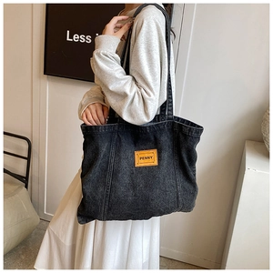 Close-up of vintage washed black denim tote bag with leather Penny brand tag detail